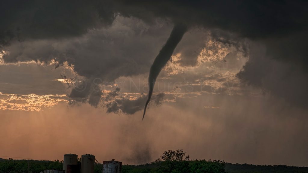 A small but persistent tornado churns up the land at sunset in Graham, Texas. This was shot during a storm chasing, weather and photography tour.