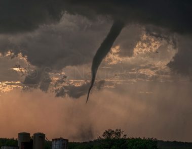 A small but persistent tornado churns up the land at sunset in Graham, Texas. This was shot during a storm chasing, weather and photography tour.