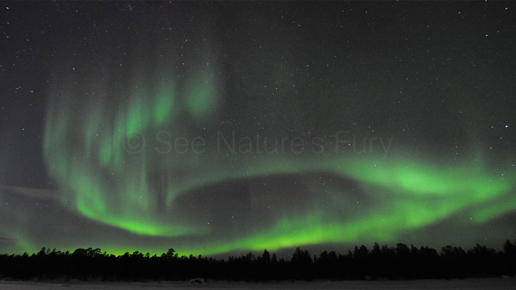 A band of northern lights swirl above a forest in lapland, Finland. This was shot during a storm chasing, weather and photography tour.