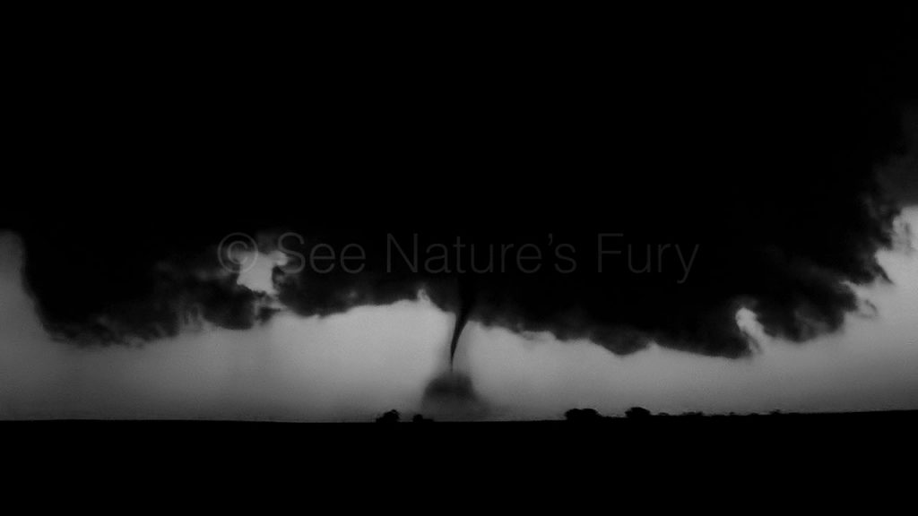 An eerie tornado at night with debris being thrown around near La Crosse, Kansas. This was shot during a storm chasing, weather and photography tour.