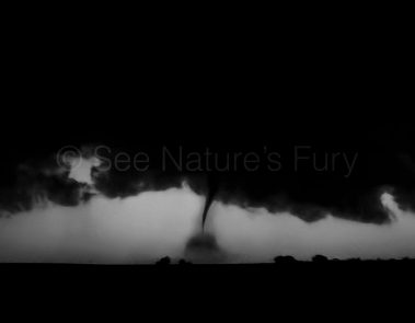 An eerie tornado at night with debris being thrown around near La Crosse, Kansas. This was shot during a storm chasing, weather and photography tour.